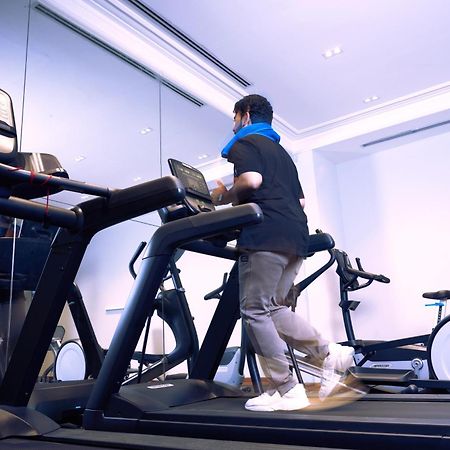 Makarem Ajyad Makkah Hotel La Meca Exterior foto The photo shows a person exercising on a treadmill in a modern gym or fitness room. The individual is wearing a blue neck support while jogging on the treadmill, which is set against a backdrop of large mirrors. There are also additional exercise equ
