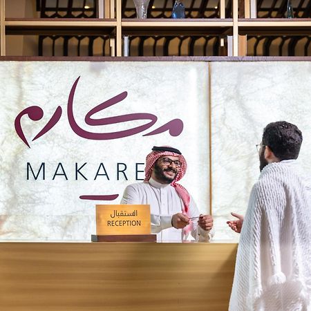 Makarem Ajyad Makkah Hotel La Meca Exterior foto The photo depicts a reception area in a hotel or establishment named "Makarem." In the image, a receptionist, dressed in traditional attire, is smiling and interacting with a guest who is wearing a white robe, commonly known as a thobe or ihram. The 