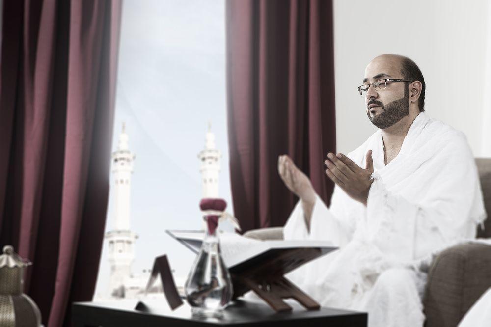 Makarem Ajyad Makkah Hotel La Meca Exterior foto The photo depicts a man sitting in a room, wearing traditional white garments typically associated with the Hajj pilgrimage. He appears to be engaged in a prayer or spiritual practice, with his hands raised in a gesture of supplication. In the backgr