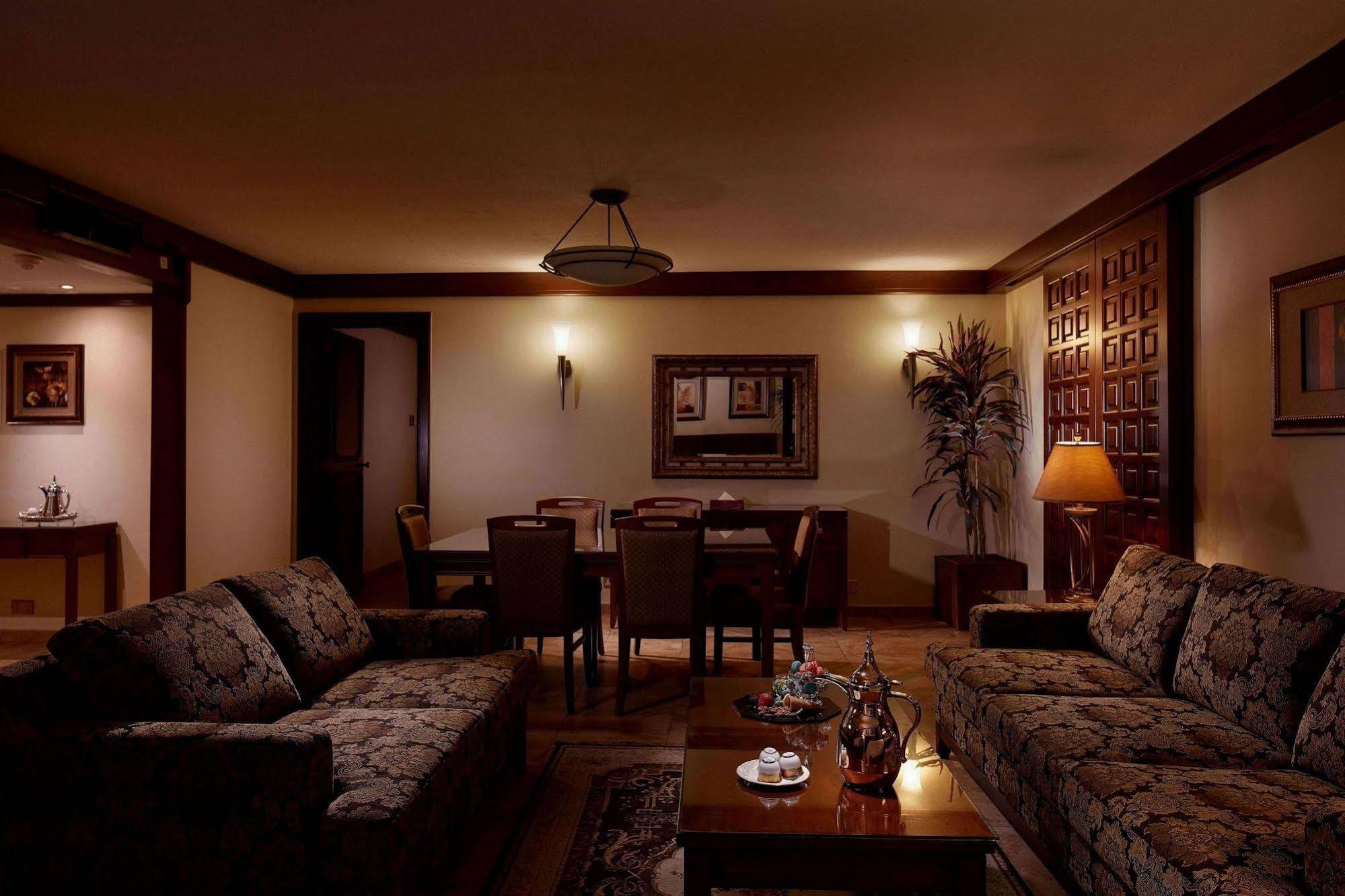 Makarem Ajyad Makkah Hotel La Meca Exterior foto The photo depicts a cozy living room setting. It features two patterned sofas facing each other with a wooden coffee table in the center. The room is softly illuminated, creating a warm atmosphere. On the walls, there are decorative elements, includi