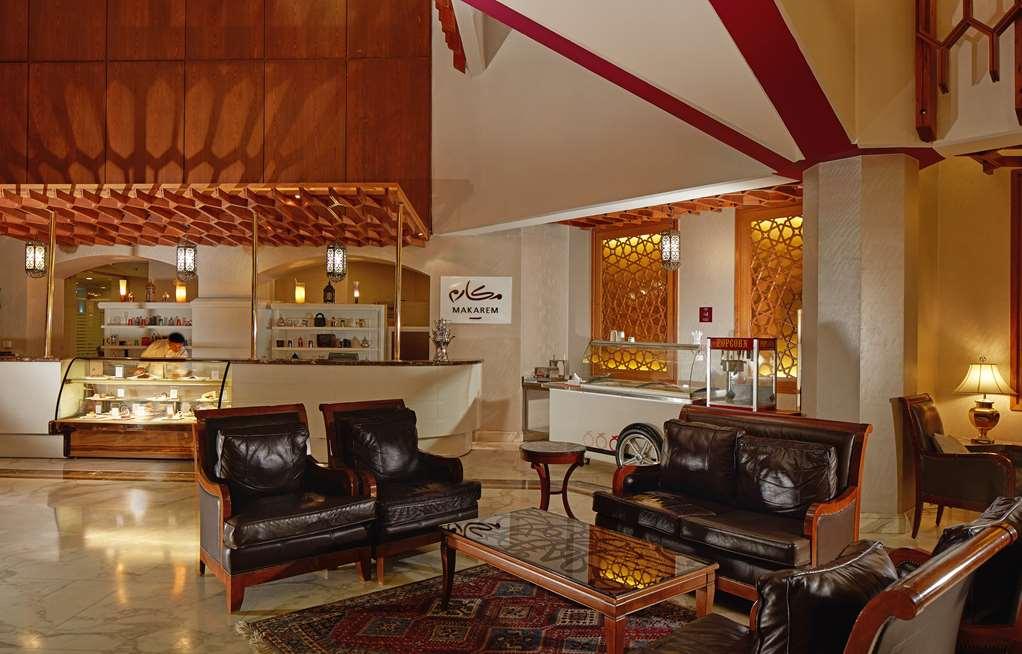 Makarem Ajyad Makkah Hotel La Meca Interior foto The photo shows a stylish interior of a lobby or lounge area. It features a seating arrangement with dark leather armchairs and a wooden table in front of them. The decor includes an intricate ceiling design and decorative wall elements that add a wa