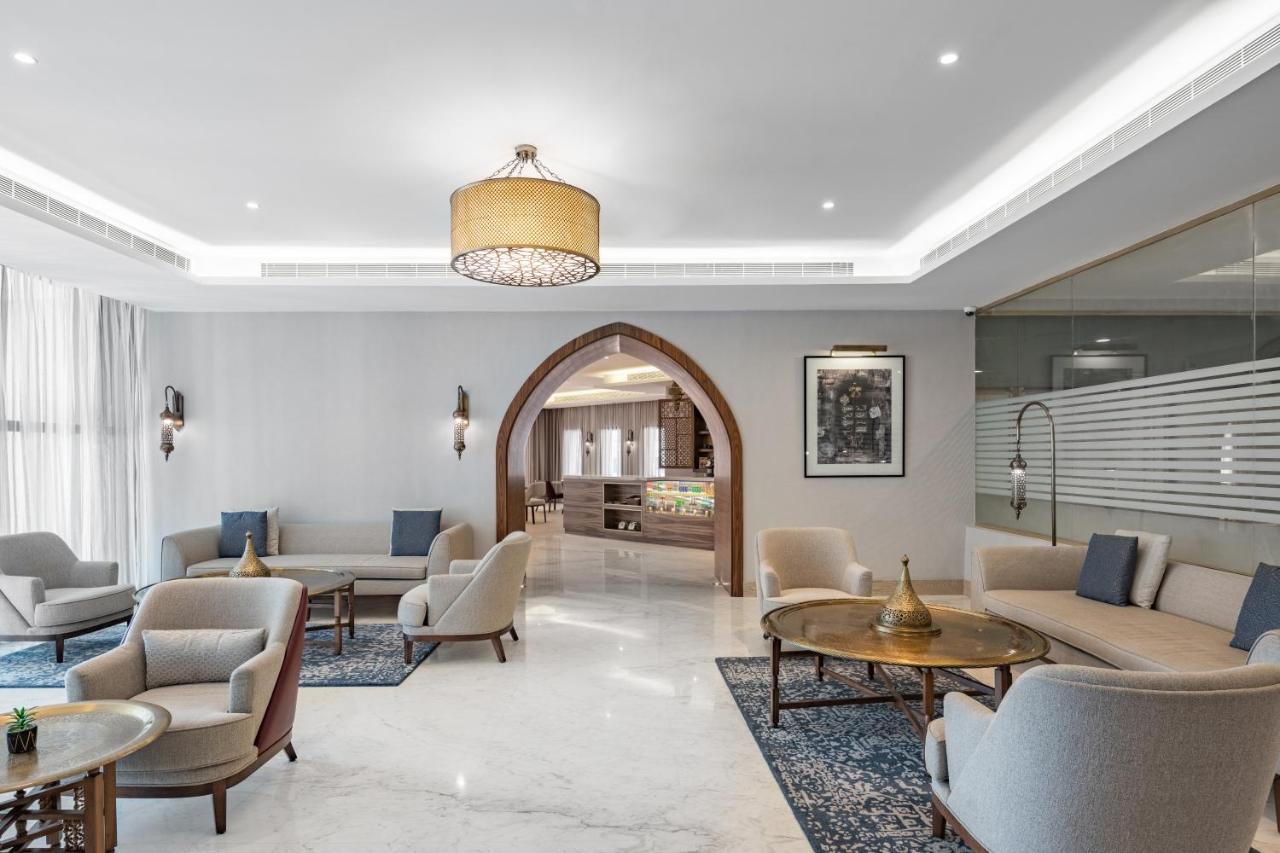 Makarem Ajyad Makkah Hotel La Meca Exterior foto The photo shows a modern and elegantly designed lounge area. It features light-colored walls and marble flooring, complemented by stylish furniture including several armchairs and small tables. The lighting is soft, provided by a decorative chandelie