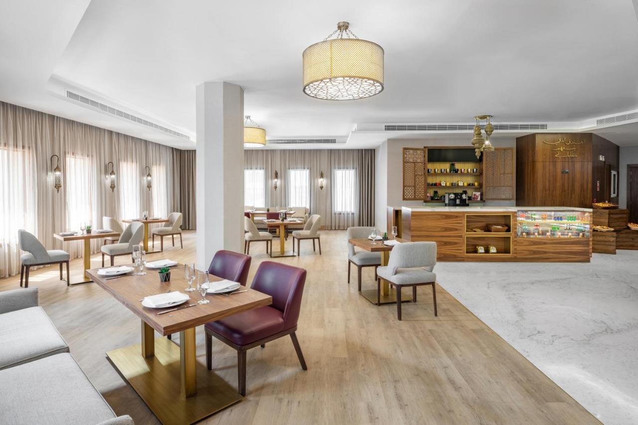 Makarem Ajyad Makkah Hotel La Meca Exterior foto The photo depicts a modern and stylish restaurant interior. The space features a combination of wooden and upholstered furniture, with several dining tables arranged throughout. The tables are set with dishes and cutlery, indicating readiness for ser