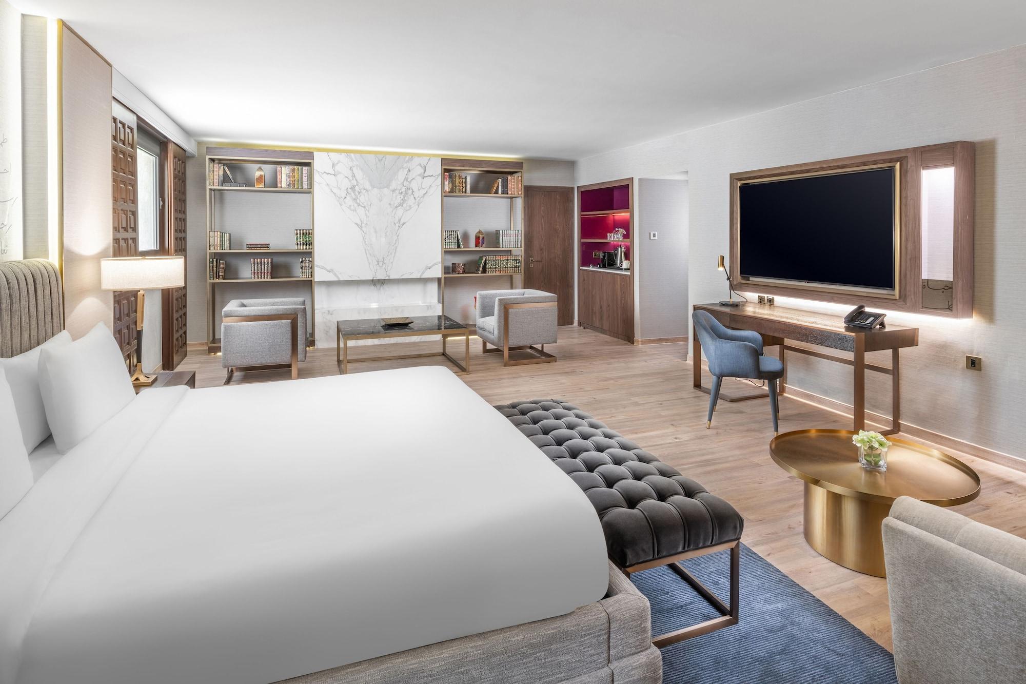 Makarem Ajyad Makkah Hotel La Meca Exterior foto The photo shows a modern hotel room designed with a contemporary aesthetic. The room features a large bed with white bedding, complemented by a stylish tufted bench at the foot of the bed. To the side, there are two comfortable armchairs positioned a