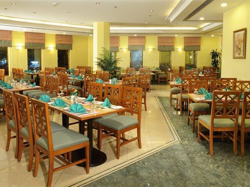 Makarem Ajyad Makkah Hotel La Meca Exterior foto The photo shows an interior view of a restaurant. It features wooden tables and chairs arranged neatly throughout the space. Each table is set with turquoise napkins, contributing to the overall decor. The walls are painted a soft yellow, and there a
