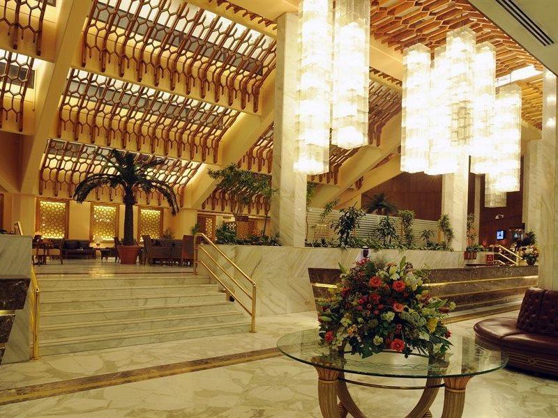 Makarem Ajyad Makkah Hotel La Meca Exterior foto The photo shows a luxurious hotel lobby with elegant design features. It has high ceilings adorned with wooden beams and large, decorative light fixtures hanging from above. The lobby is brightly lit, creating a warm and inviting atmosphere. There ar