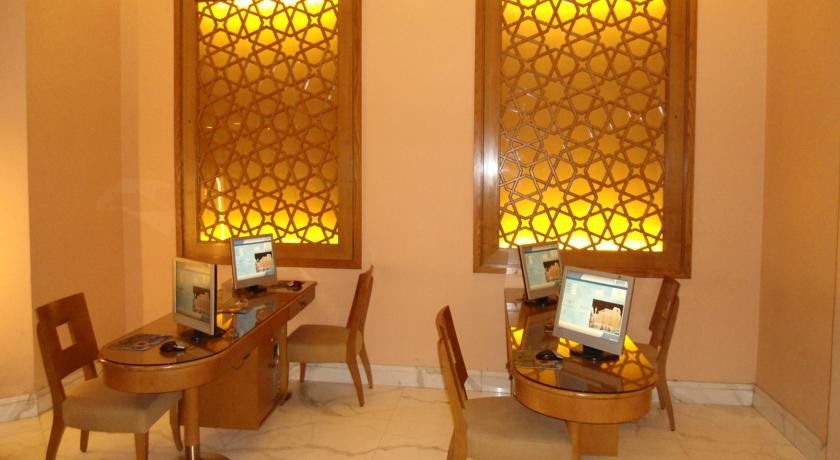 Makarem Ajyad Makkah Hotel La Meca Exterior foto The image shows a room with a warm, inviting atmosphere, featuring two wooden desks equipped with computers. Each desk has a chair positioned in front of it. The walls are adorned with decorative panels that exhibit intricate patterns, illuminated by