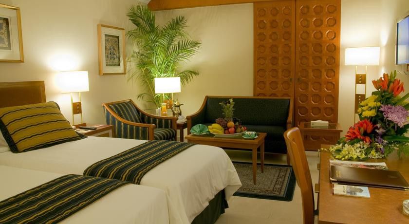 Makarem Ajyad Makkah Hotel La Meca Exterior foto The photo shows a cozy hotel room that features two single beds with white linens and dark green and striped blankets. There is a decorative rug on the floor. Against one wall, there is a large wooden partition with a distinctive geometric pattern. T