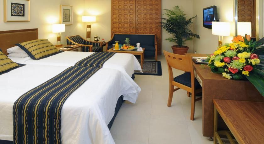 Makarem Ajyad Makkah Hotel La Meca Exterior foto The image shows a hotel room featuring two beds with white linens and a decorative stripe along the edge. There is a seating area with two chairs and a small table, set with a breakfast spread that includes fruit and drinks. A small potted plant adds